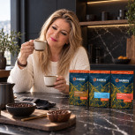 Juana María compara dos cafés junto al pack Ruta del Cacao en una cocina negra con mármol oscuro