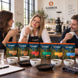Juana María comparte café con dos amigos junto al pack Mesa de Cata en un espacio de cata con mesa de nogal oscuro